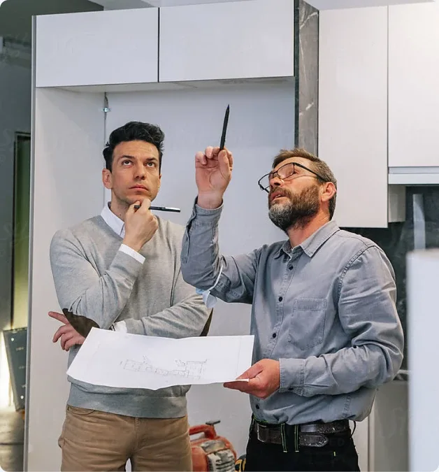 Zwei Bauleiter besprechen Baupläne und deuten auf die Decke